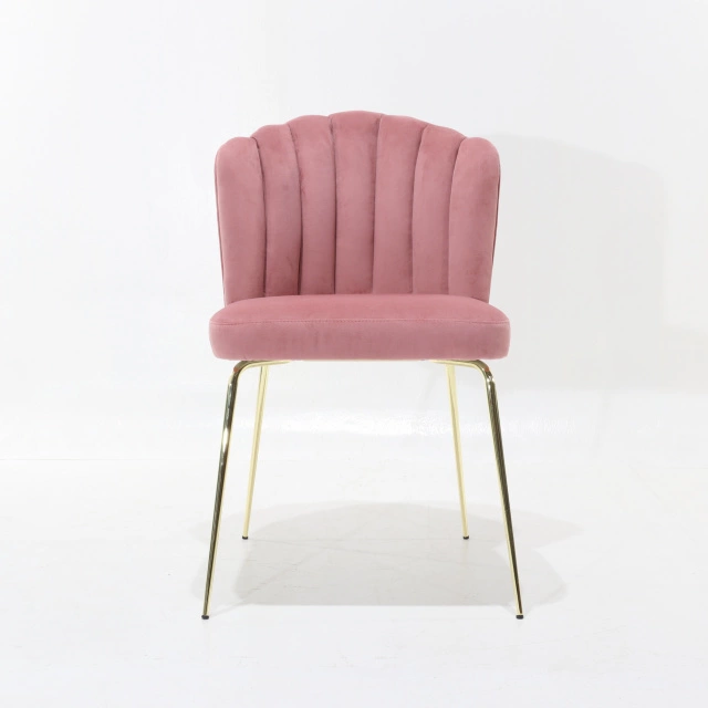 Una sedia rosa con rivestimento in velluto rosa si trova in una stanza con  un muro rosa dietro.